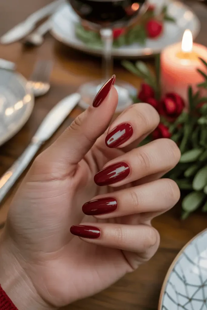 Glossy dark red chrome nails, cozy dinner table background, soft evening lighting.