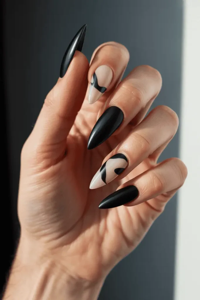 sharp stiletto nails with mixed matte and glossy black graphic shapes, bold edgy style, dramatic shadows, realistic hands, editorial lighting
