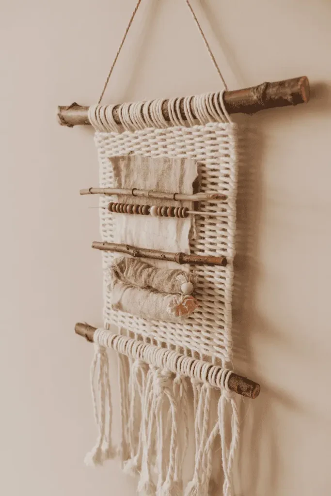 “simple handmade wall hanging using twine, sticks, fabric scraps, and beads, neutral wall background, soft spring daylight, organic handmade style, realistic photography, no text, 2:3 vertical”