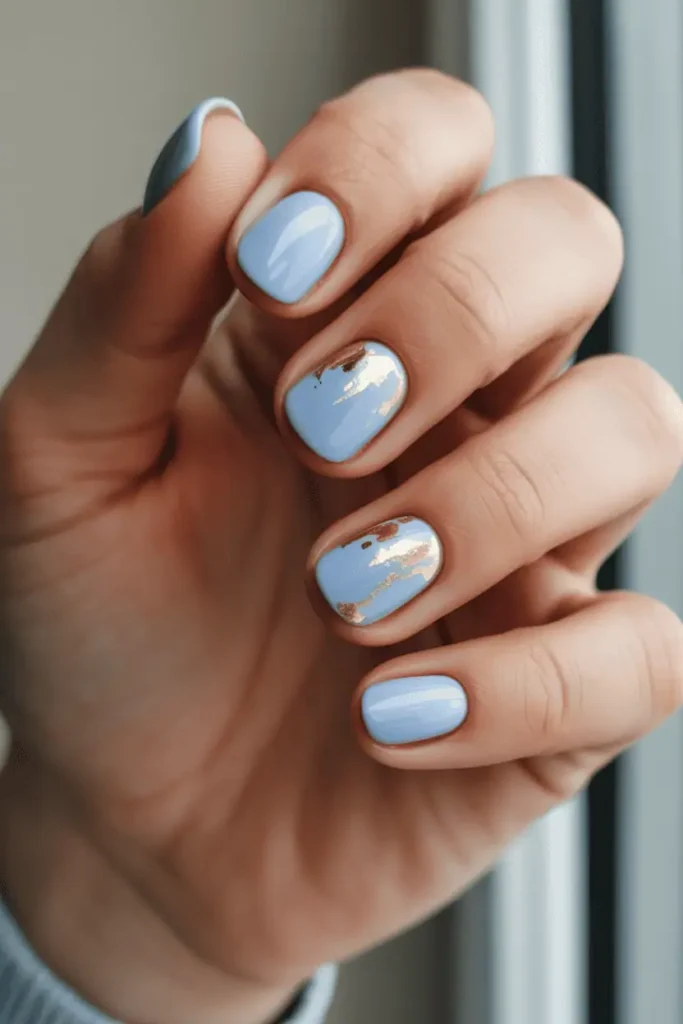 baby blue pastel nails with subtle gold foil accents, glossy finish, elegant spring nail design, short to medium nails, soft natural lighting, neutral background, editorial nail photography, pinterest vertical 2:3 ratio, no text