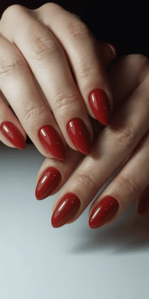 Glossy cherry red polish on almond-shaped nails, timeless Valentine's Day manicure with high-shine finish