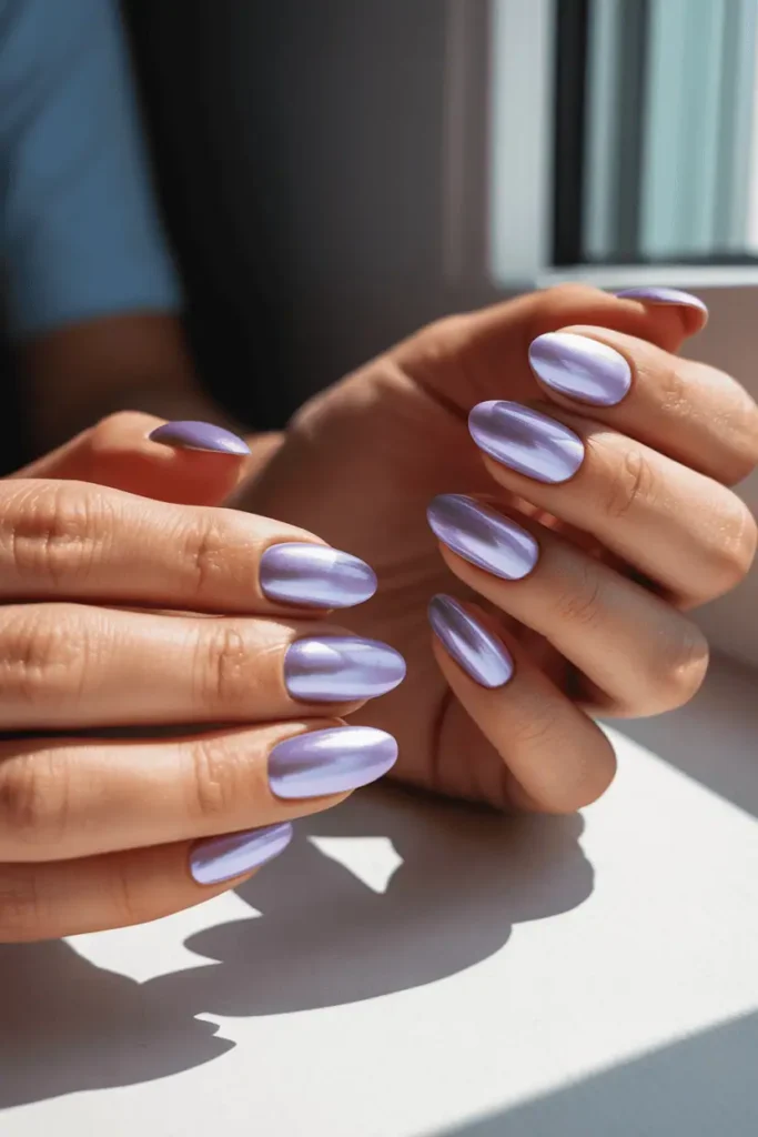 pastel lavender chrome nails with soft pearlescent glow, realistic hands, bright natural light, minimal spring decor, high-quality reflection