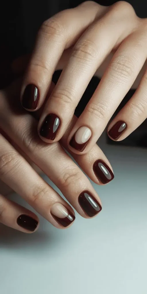 Short square nails featuring burgundy half-moon manicure with nude negative space near cuticles, minimalist Valentine's nail art