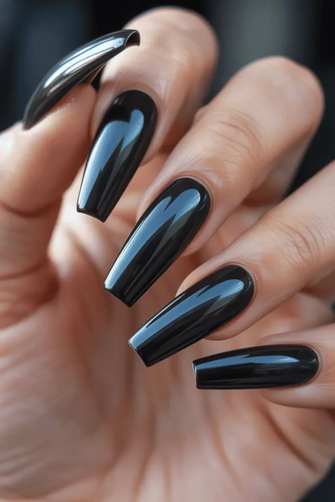 long coffin nails painted in glossy jet black, dramatic shine, bold modern look, soft blurry background, realistic hands, high-impact lighting, Pinterest hero photo