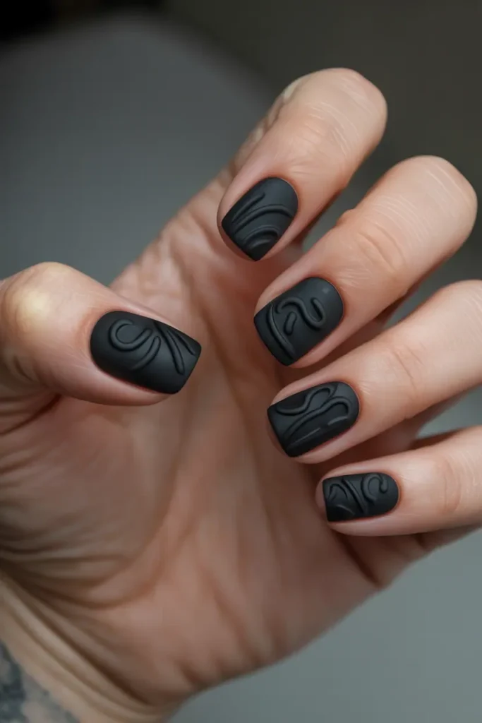 black nails with raised 3D matte embossed designs, sculpted lines and curves, tactile modern look, minimal background, realistic hands, soft directional lighting